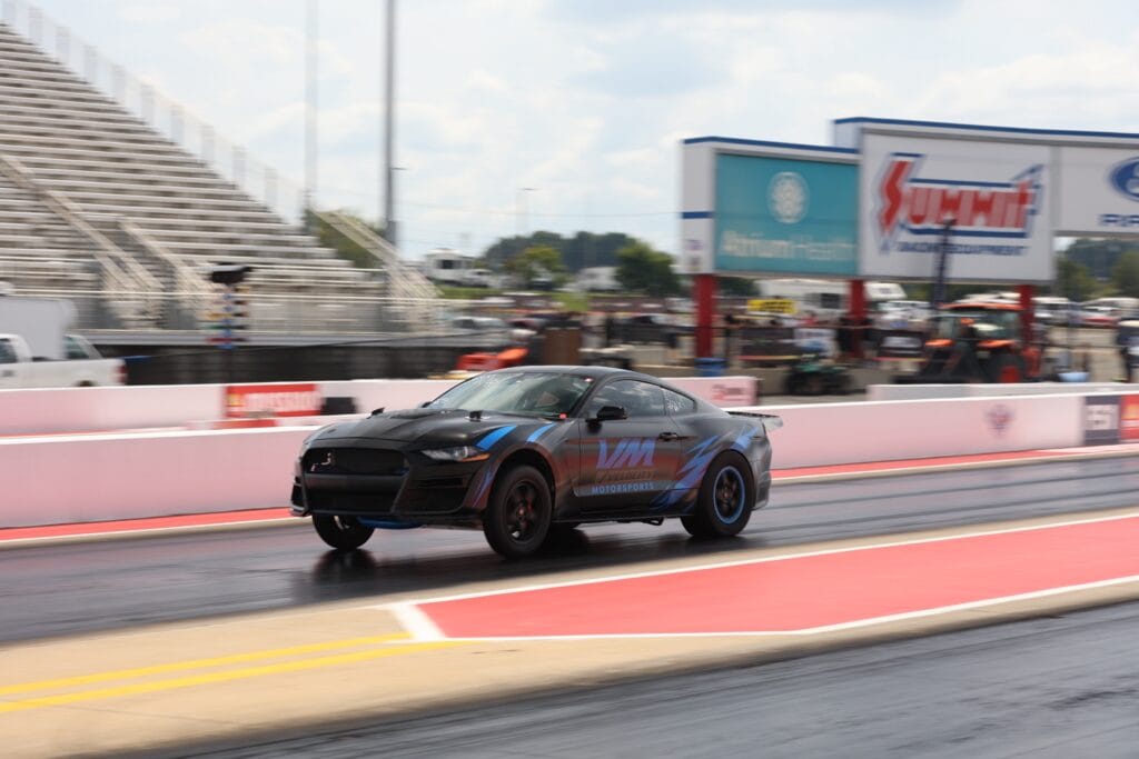 Black race car on drag strip at Mustang Week Charlotte 2026.