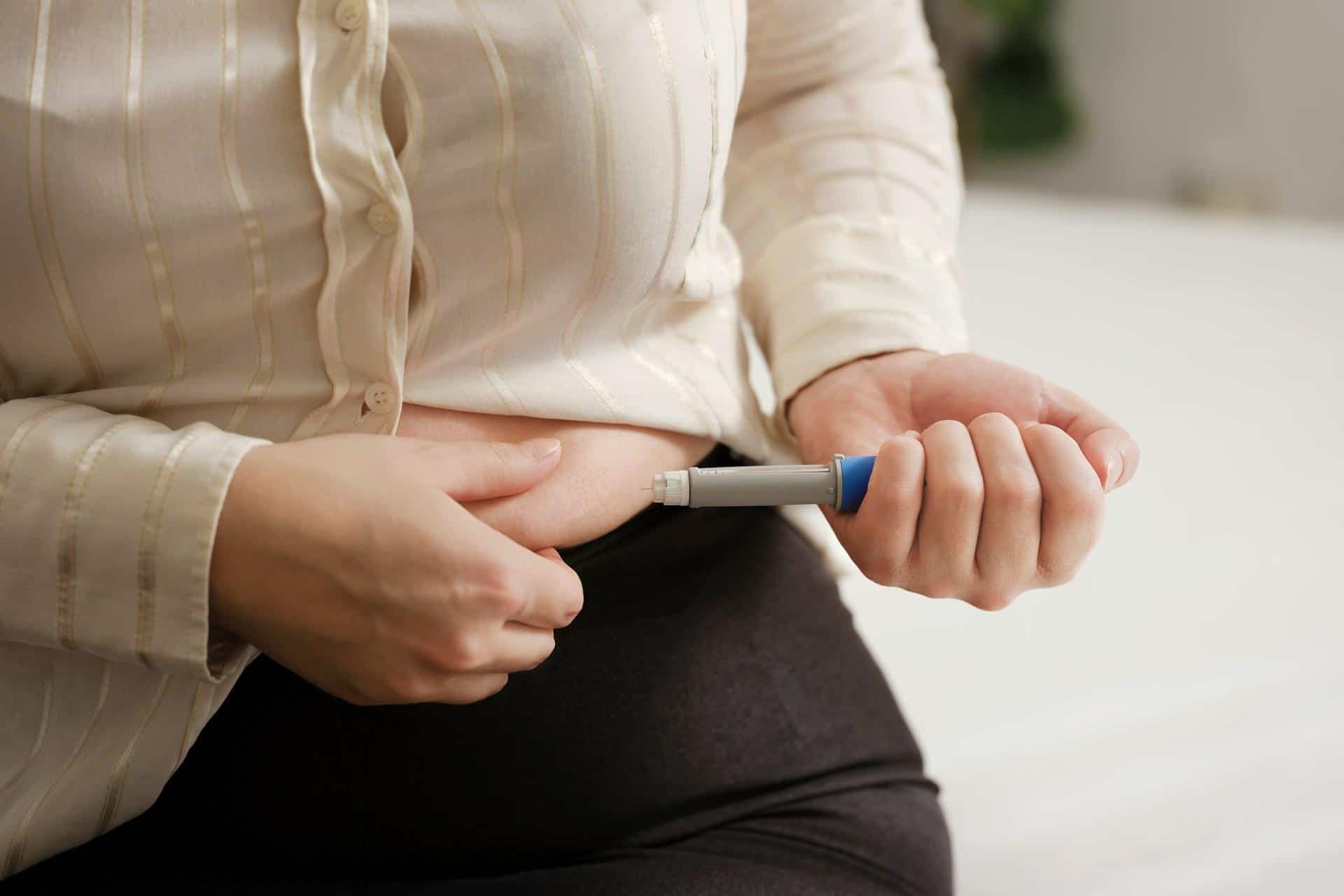 A lady injecting her stomach with a weight loss injection pen