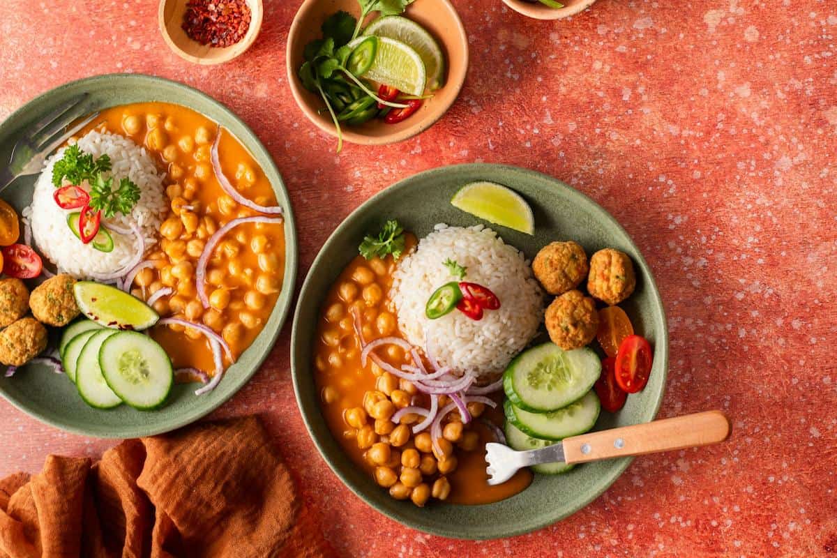 a plate of food with lentils, rice and cucumber.