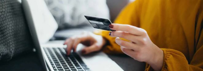 Person using credit card and laptop for online banking at Meridian Trust.
