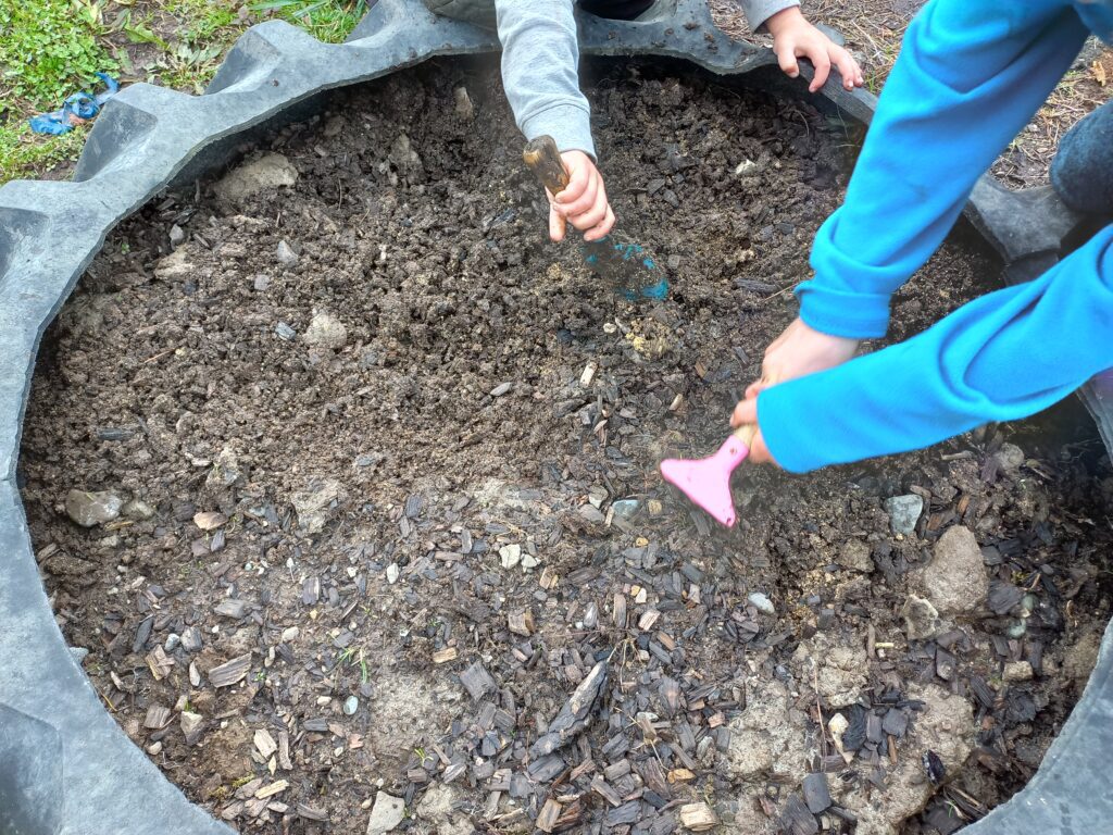 Two kids are digging in the tractor tyre garden bed