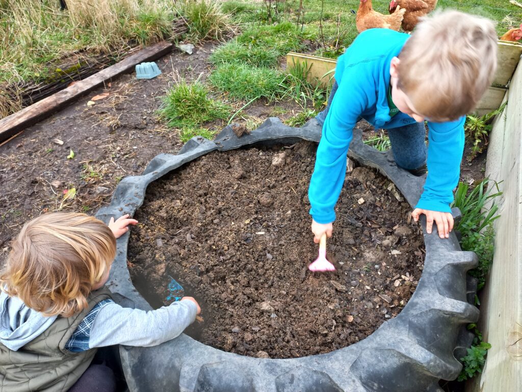 two kids planting seeds in a tyre garden bed