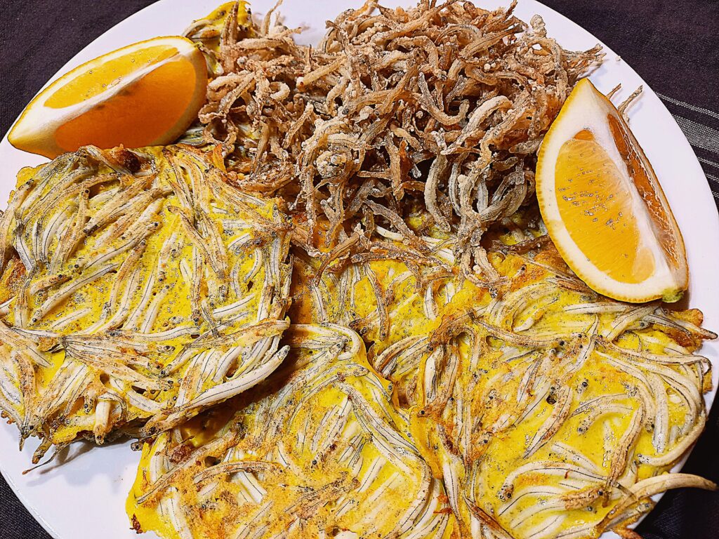 whitebait fritters and crispy fried whitebait, two lemon wedges on a white plate