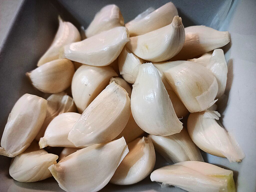 individual garlic cloves in a white square bowl