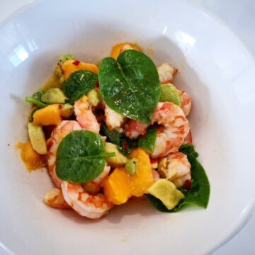 Prawn salad with mango and avocado served in a white bowl plate