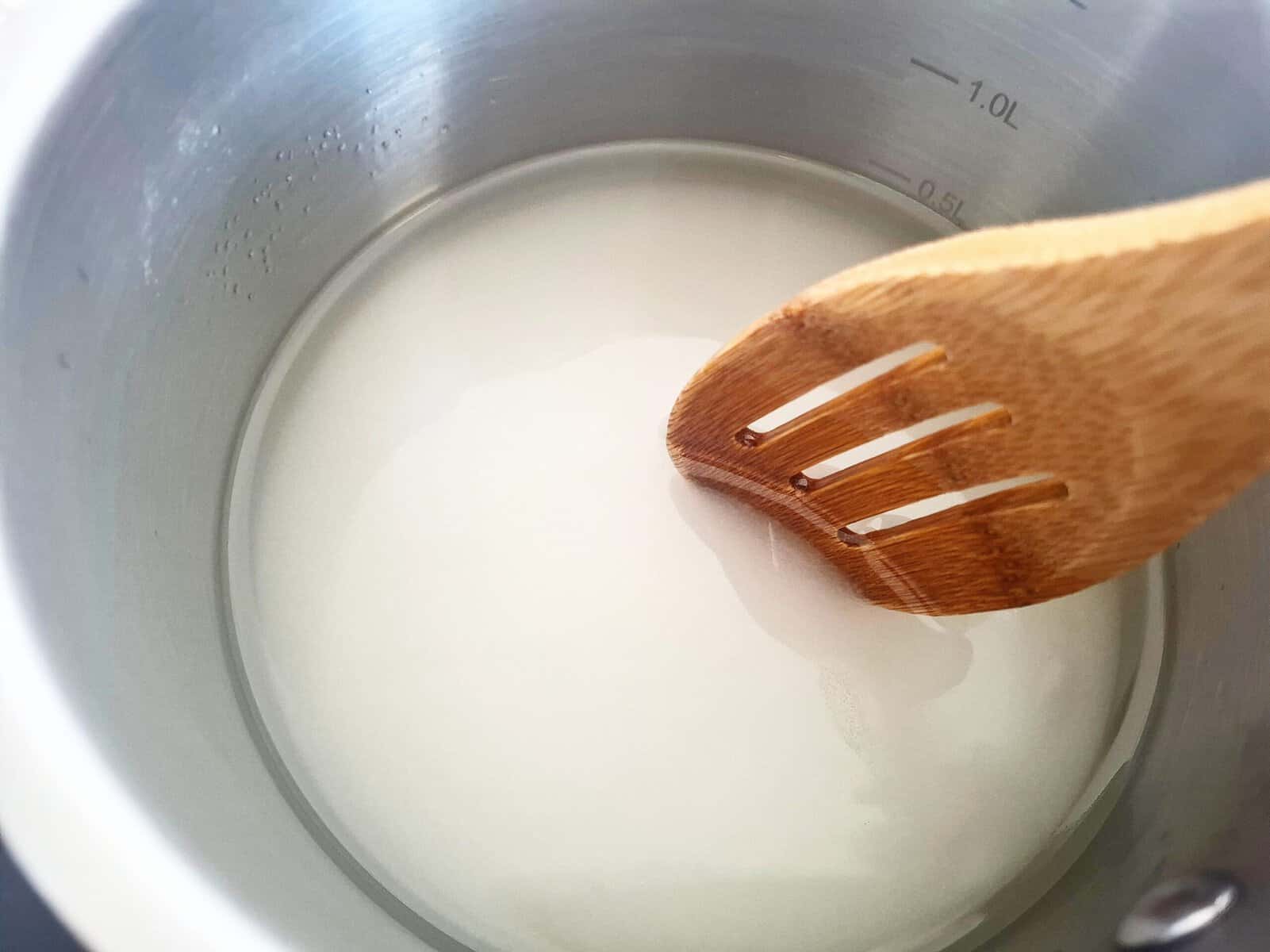 Stirring salt, sugar and rice vinegar with a wooden spoon in a sauce pan