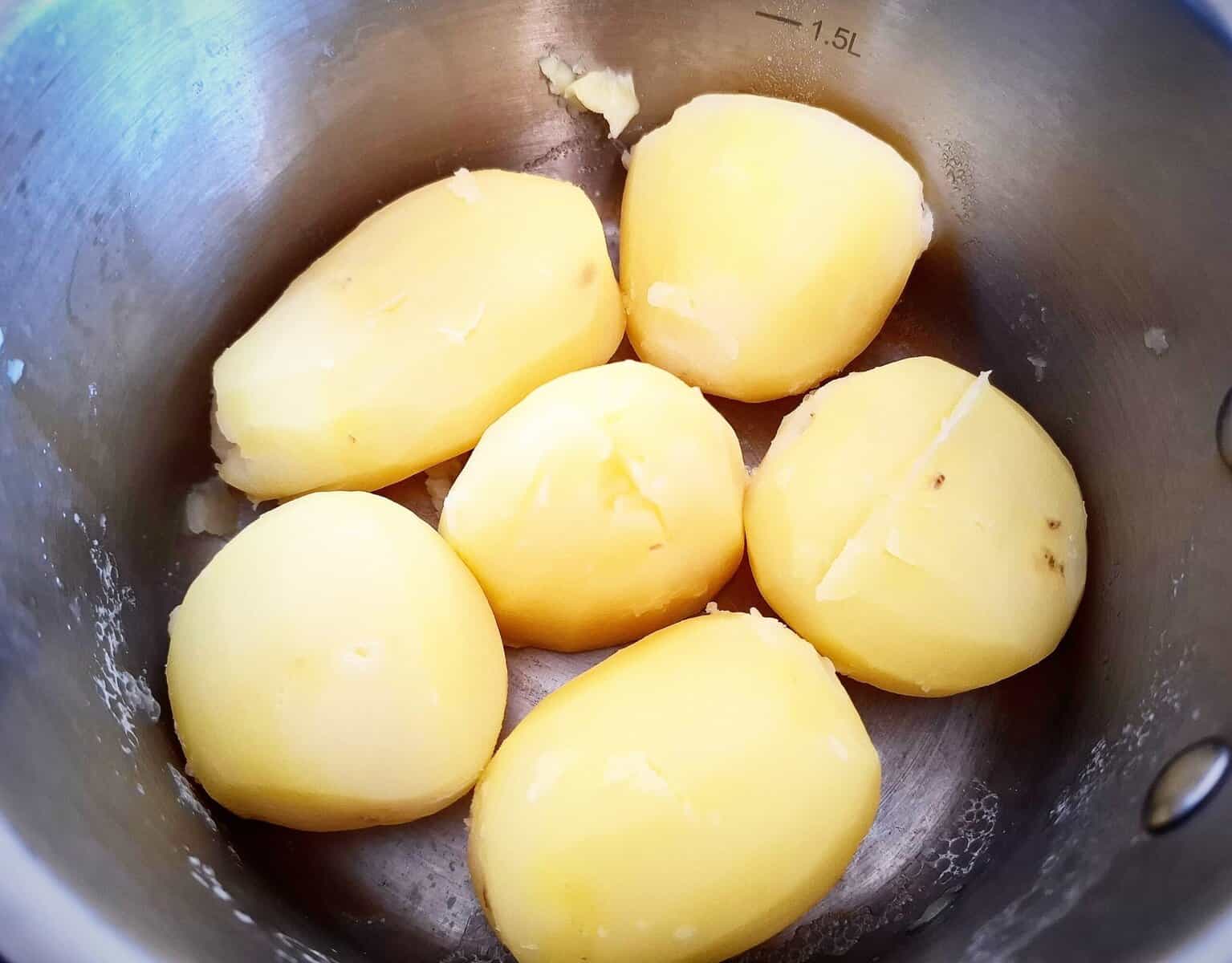 six cooked potatoes in a sauce pan