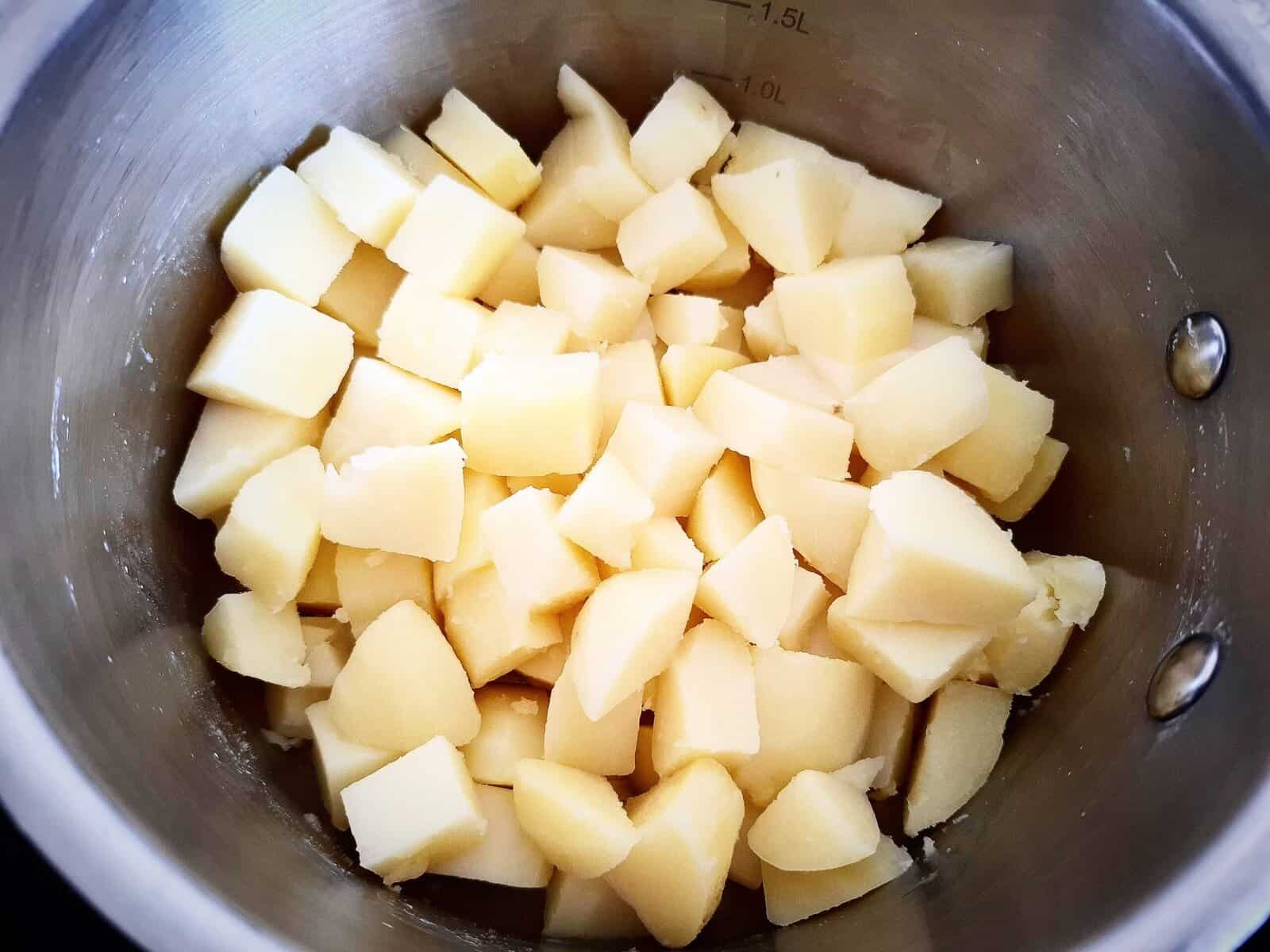 Cooked potatoes cut into 1cm pieces in a stainless steel saucepan