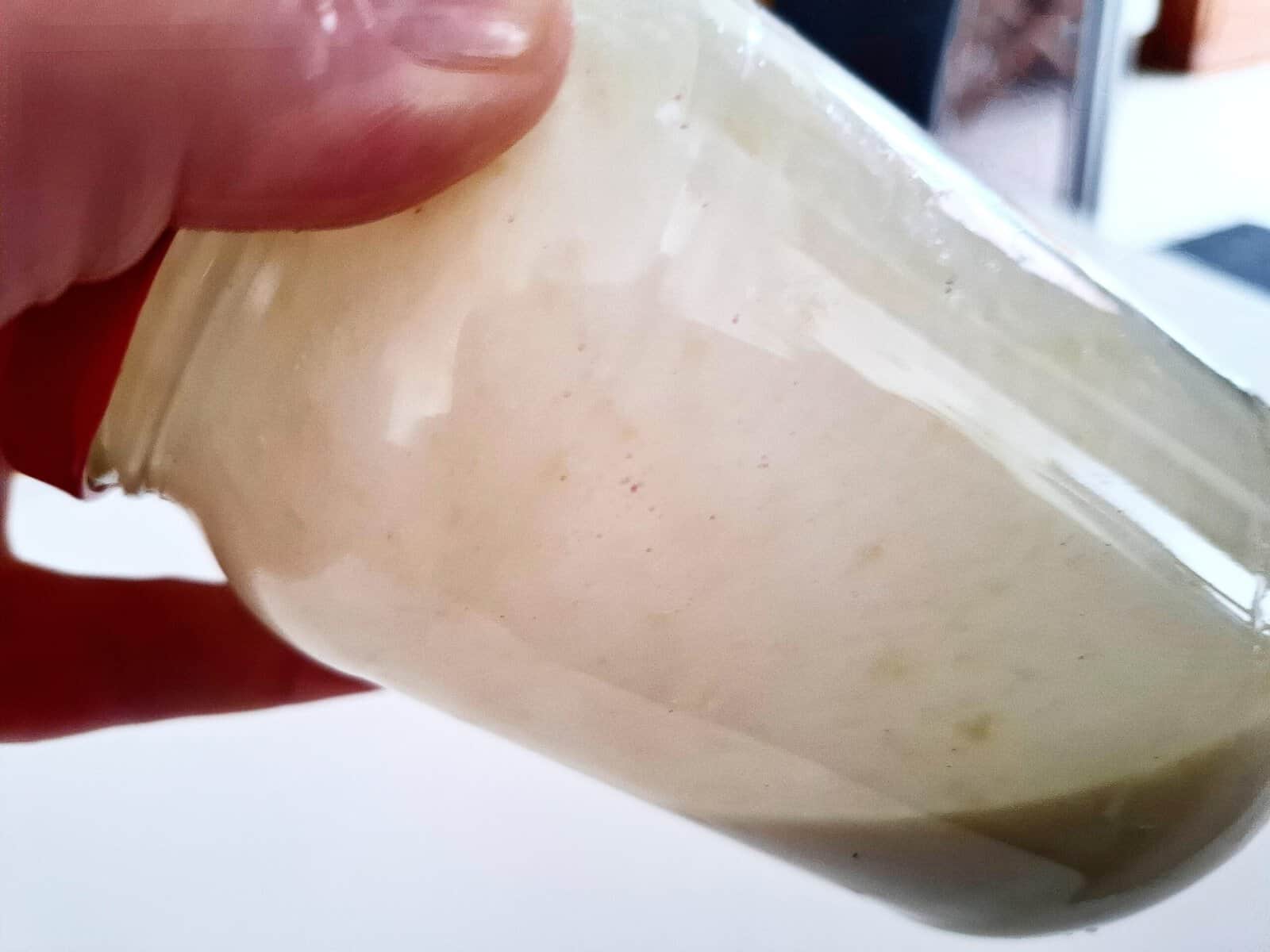 Holding a glass jar in one hand to shake the dressing ingredients inside
