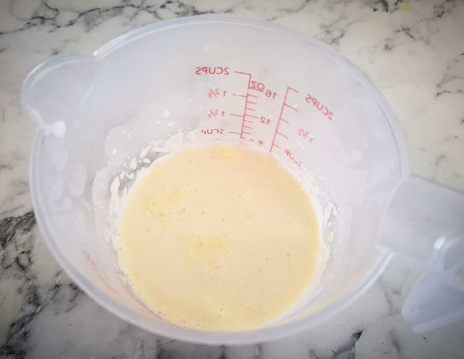 Hot cream in a plastic measuring jug on a marbled bench top