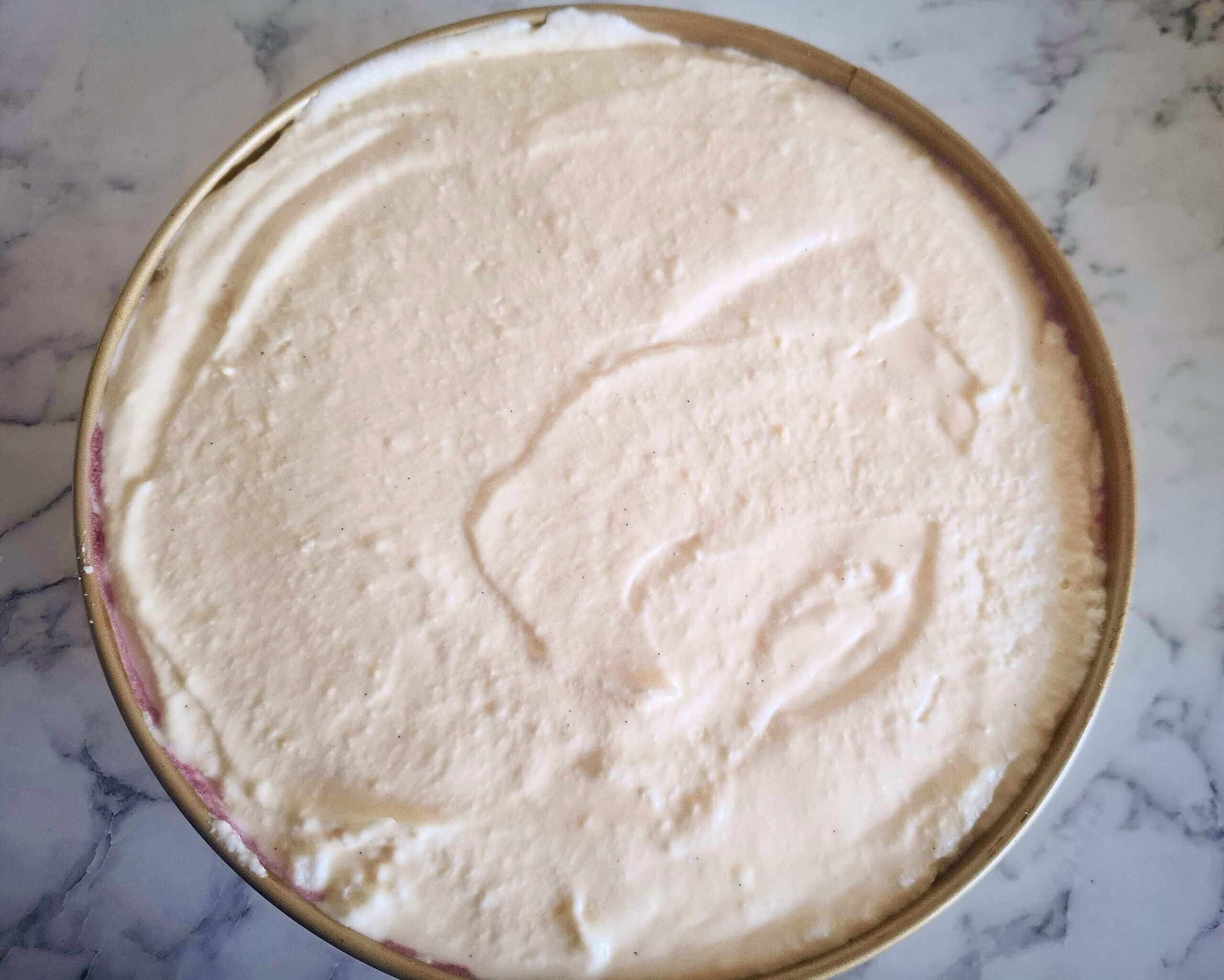 A round cake tin filled with cheese cake mixture.
