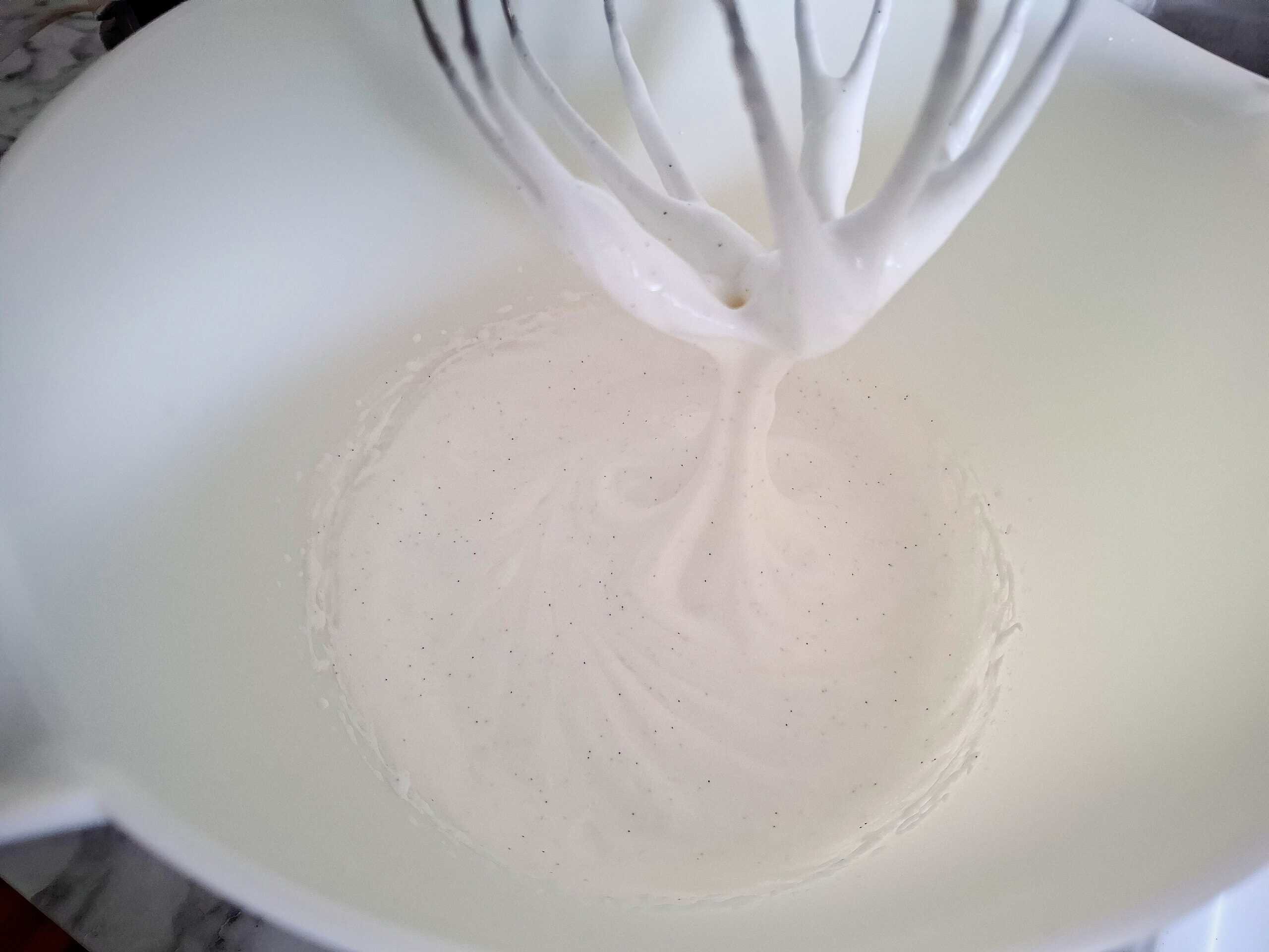 Egg whites, vanilla and sugar has been whipped pale and fluffy in a white kitchen mixer bowl with a whisk attachment