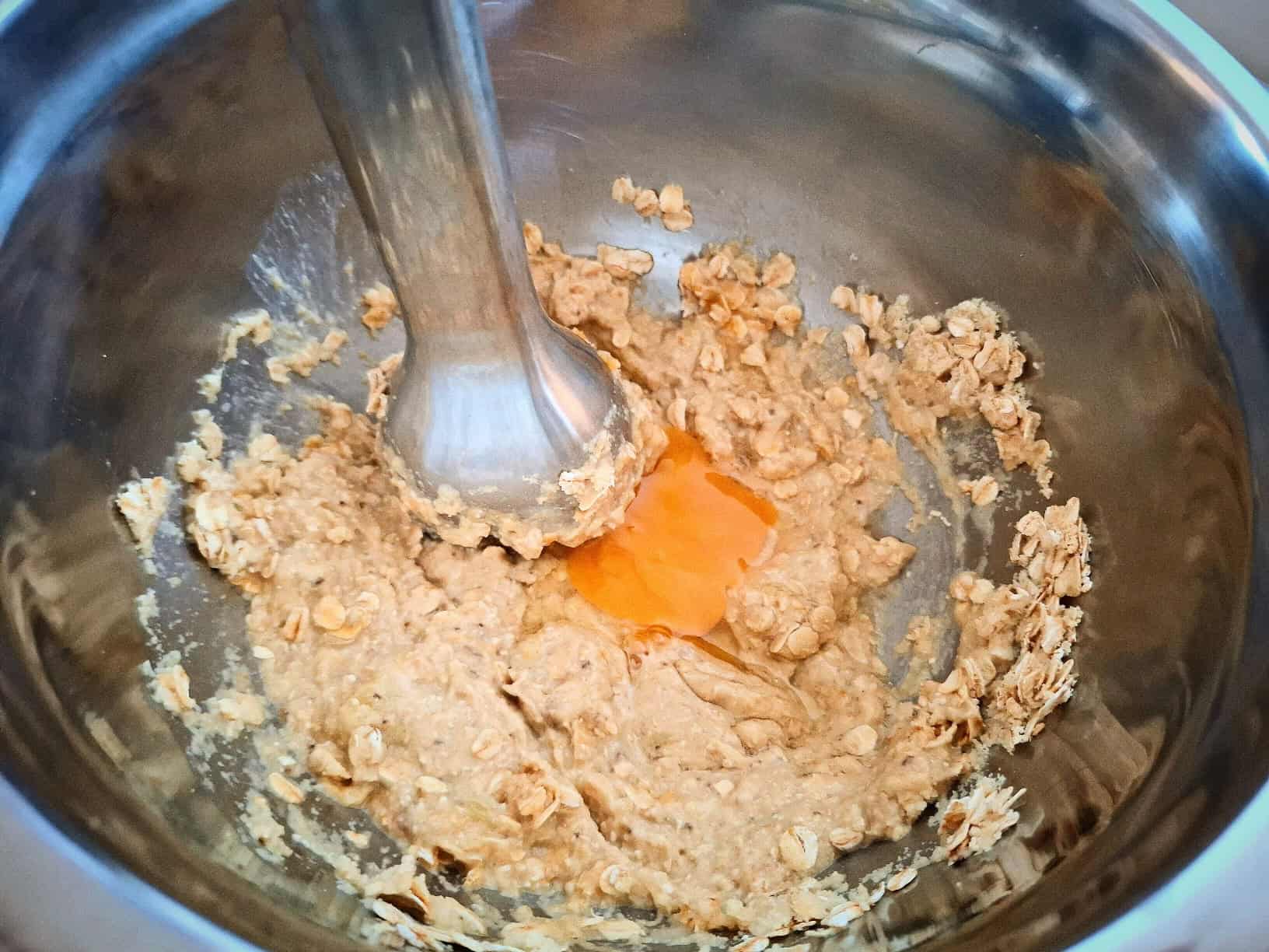 Mixing the ingredients for banana almond pancakes with a stick blender in a stainless steel bowl.