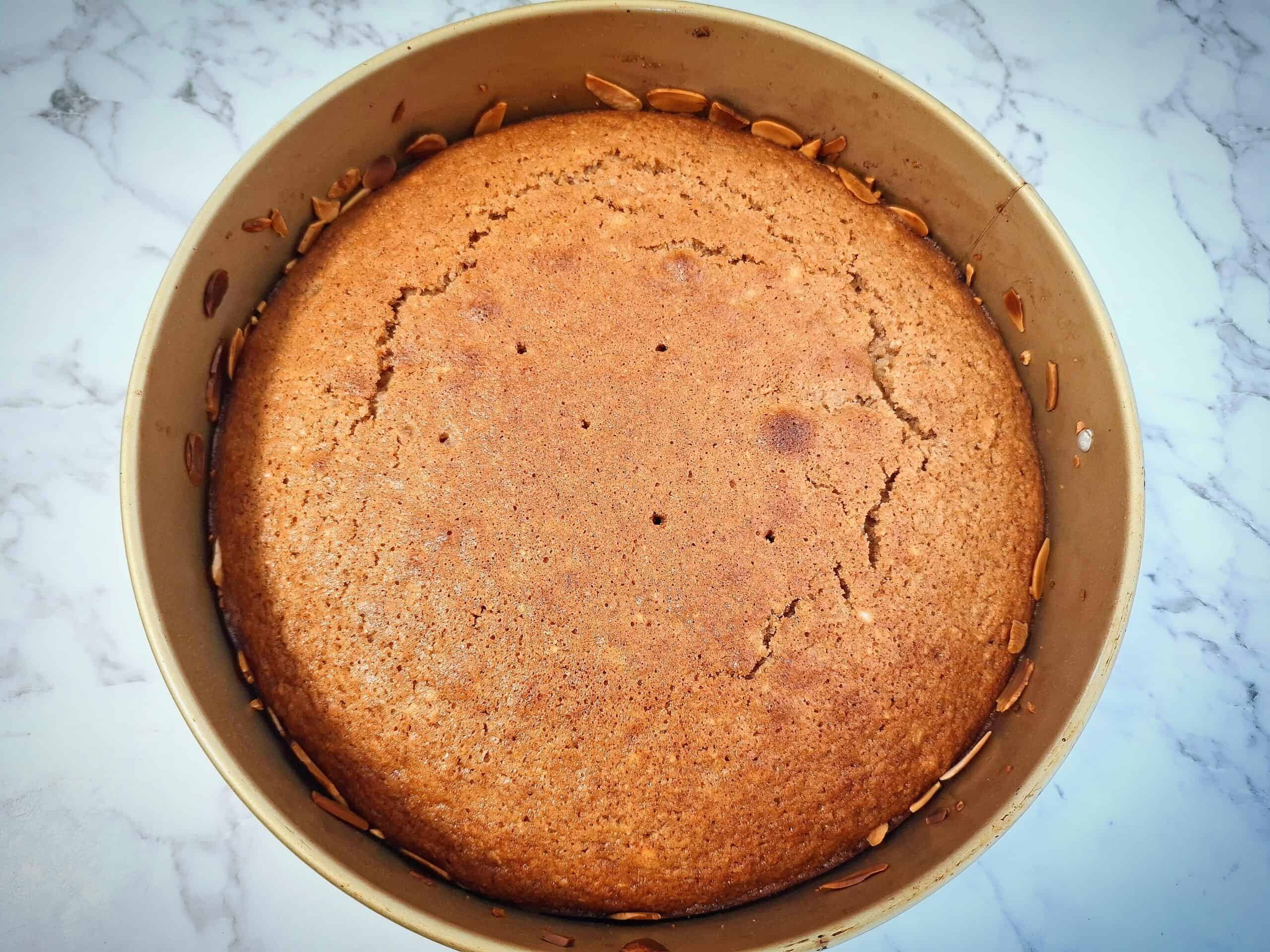 Cooked apple and almond cake in a round cake tin.