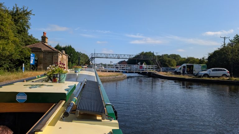 Narrowboat navigating a canal lock in the UK on a sunny day.
