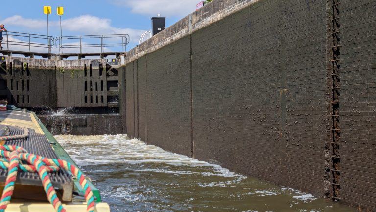 Narrowboat lock gate with water flowing through in UK.