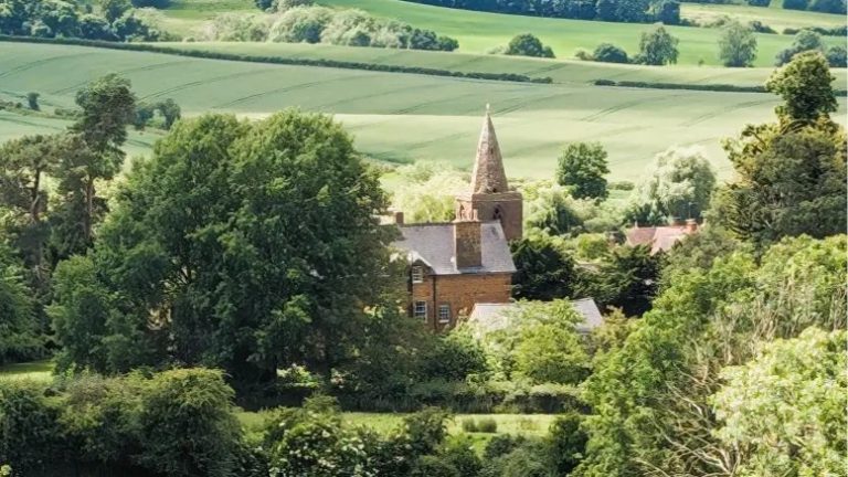 Beautiful rural landscape with a church steeple and lush green fields.