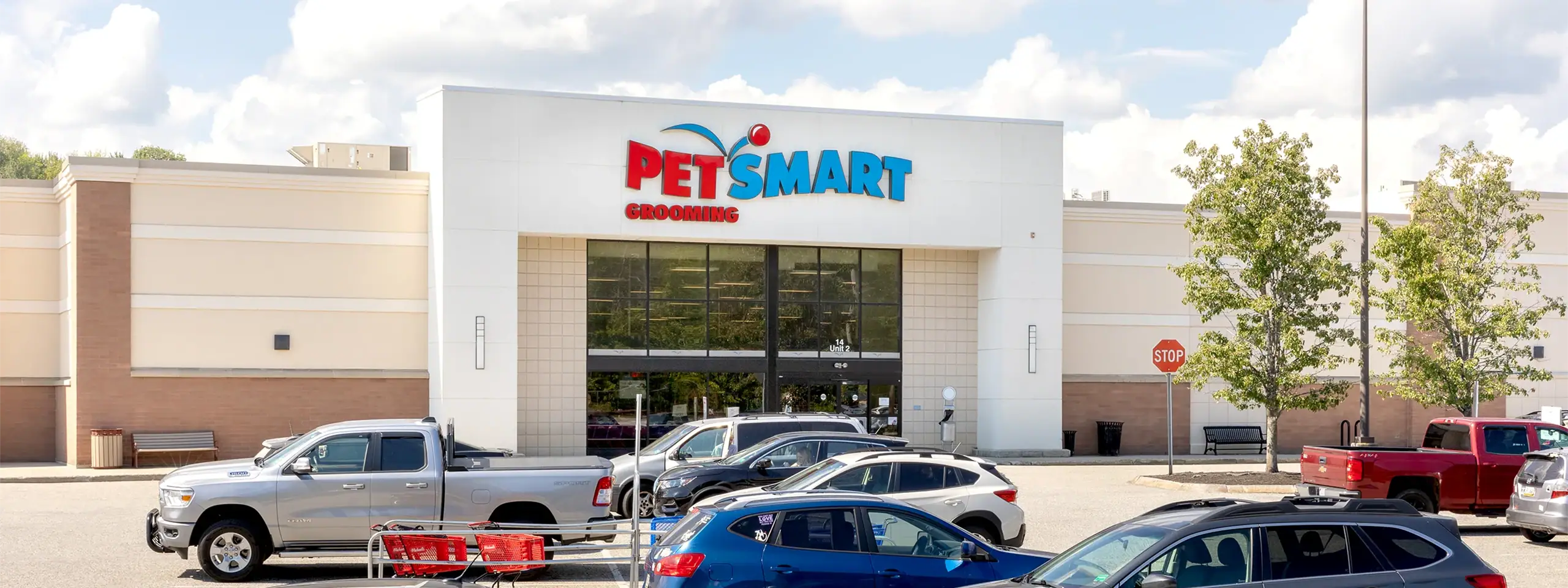 PetSmart store in a shopping center with parked cars and trees outside.