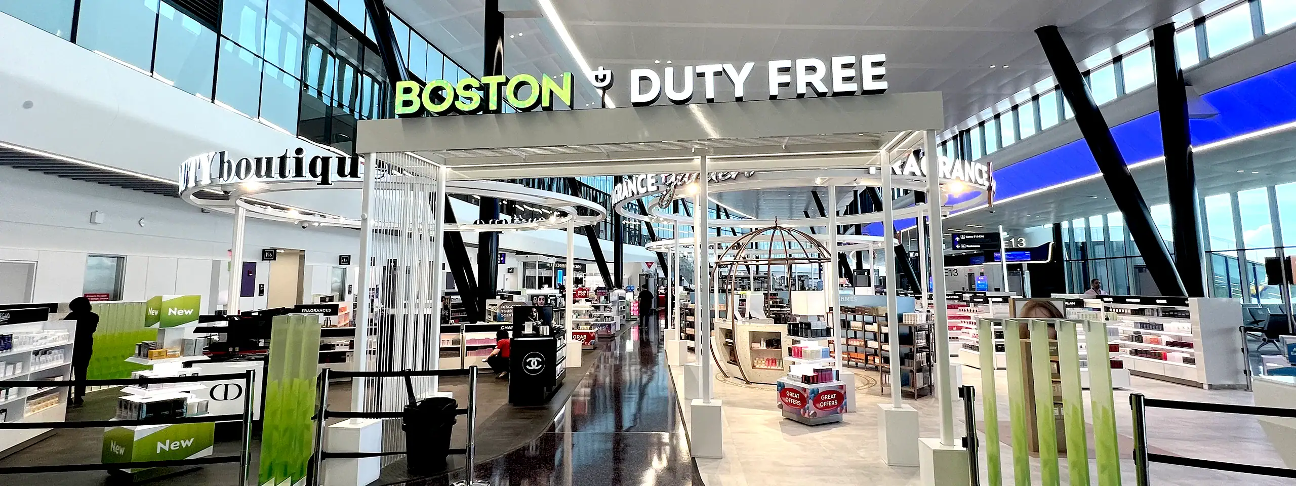 Boston Logan Airport duty-free shopping area with stores and travelers.