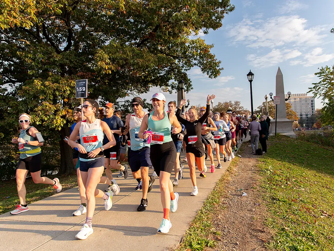 Group of runners participating in a race along a park path with trees and the Washington Monument in.