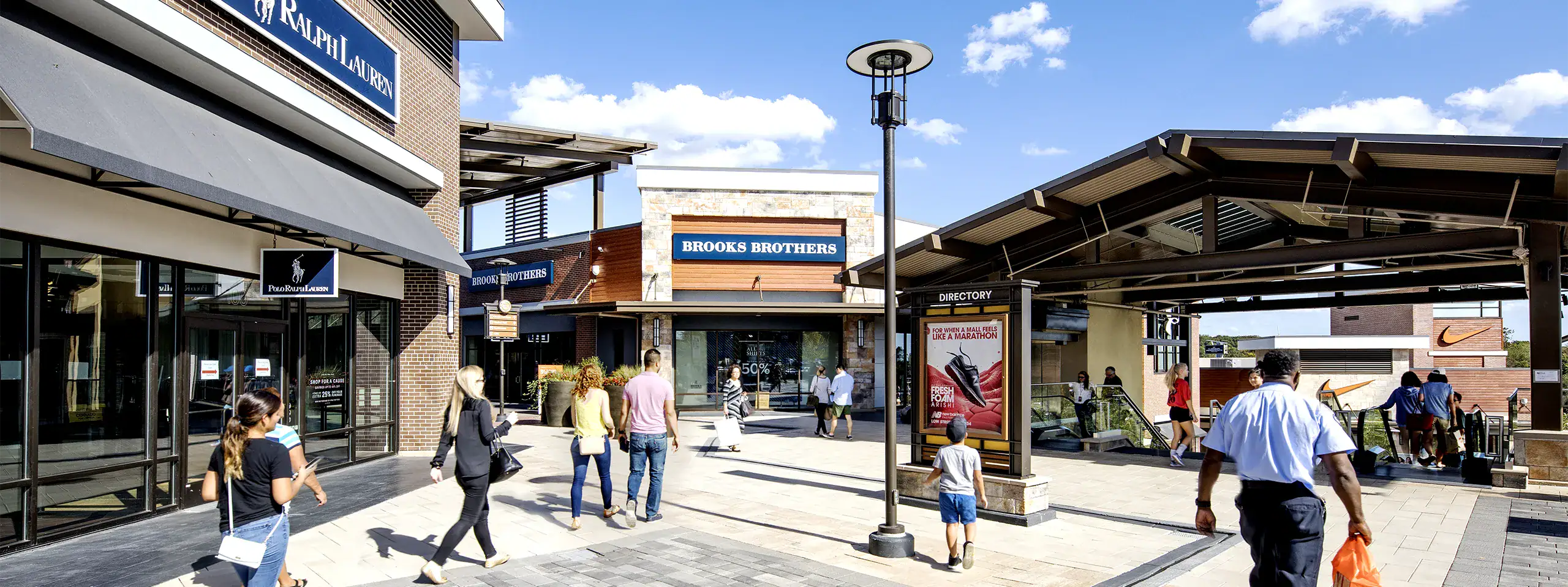 People walking and waiting at a busy outdoor transit station in New England.