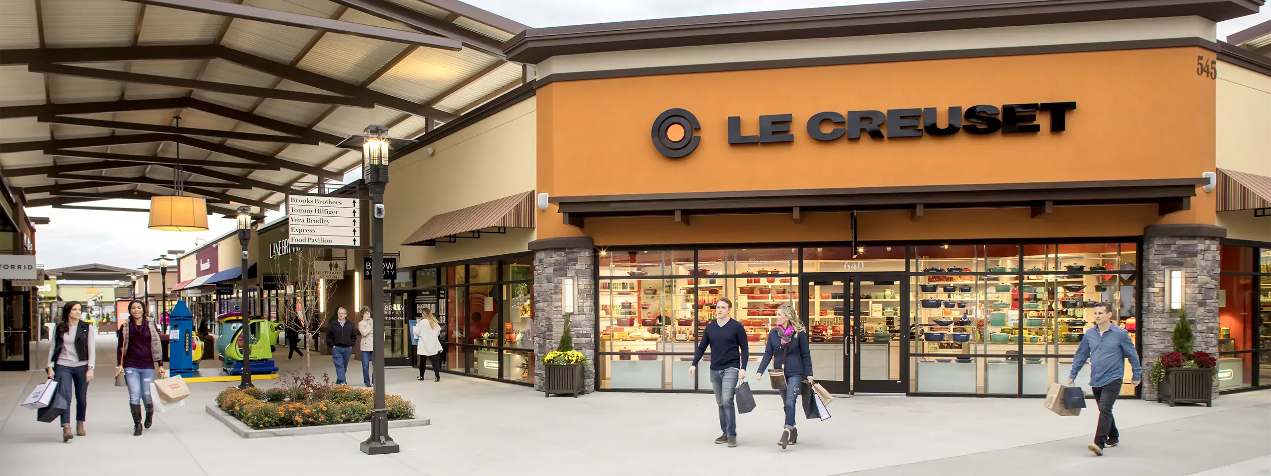 Le Creuset store with shoppers walking outside in a shopping district.