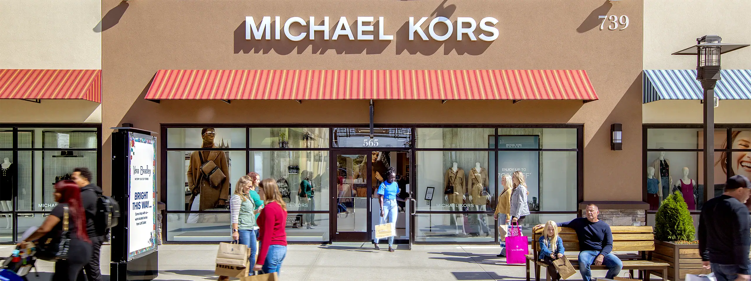 Michael Kors store with shoppers and mannequins outside in a shopping mall.