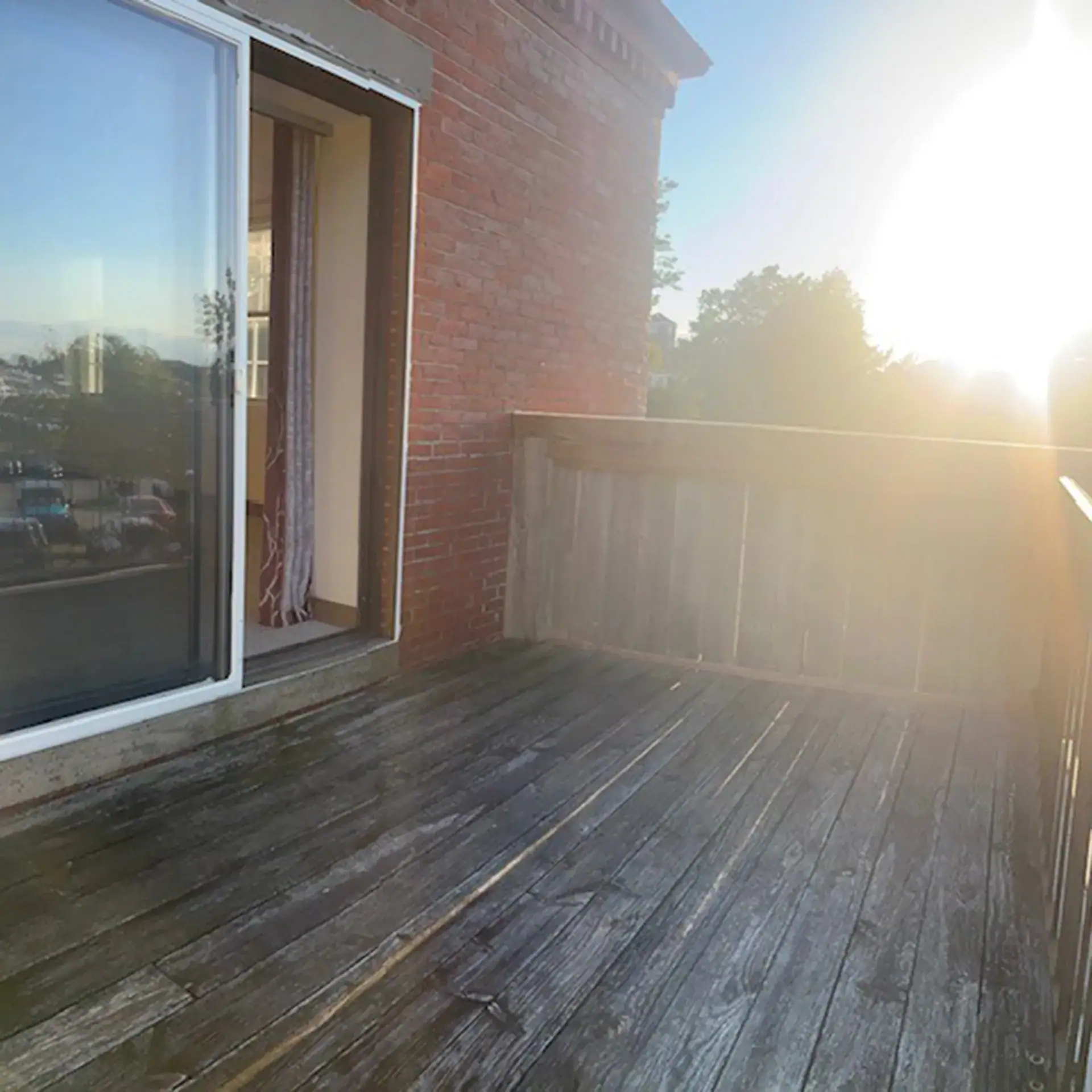 Empty wooden balcony with sliding glass door and sunset view in Newburyport.