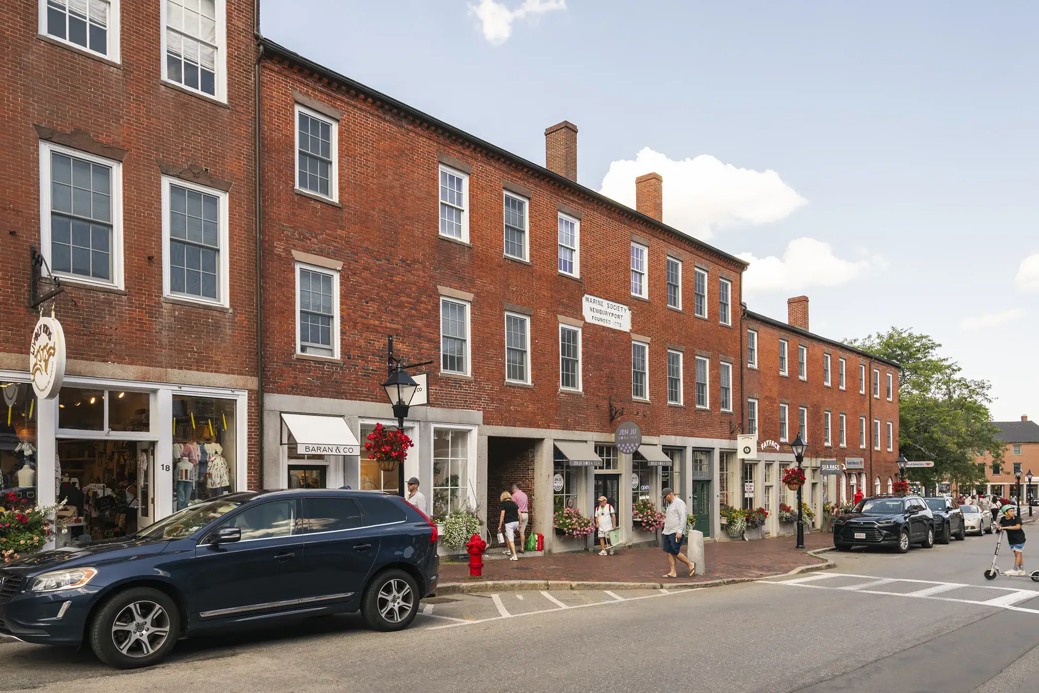 Historic brick building with shops and pedestrians on a busy street in Newburyport.