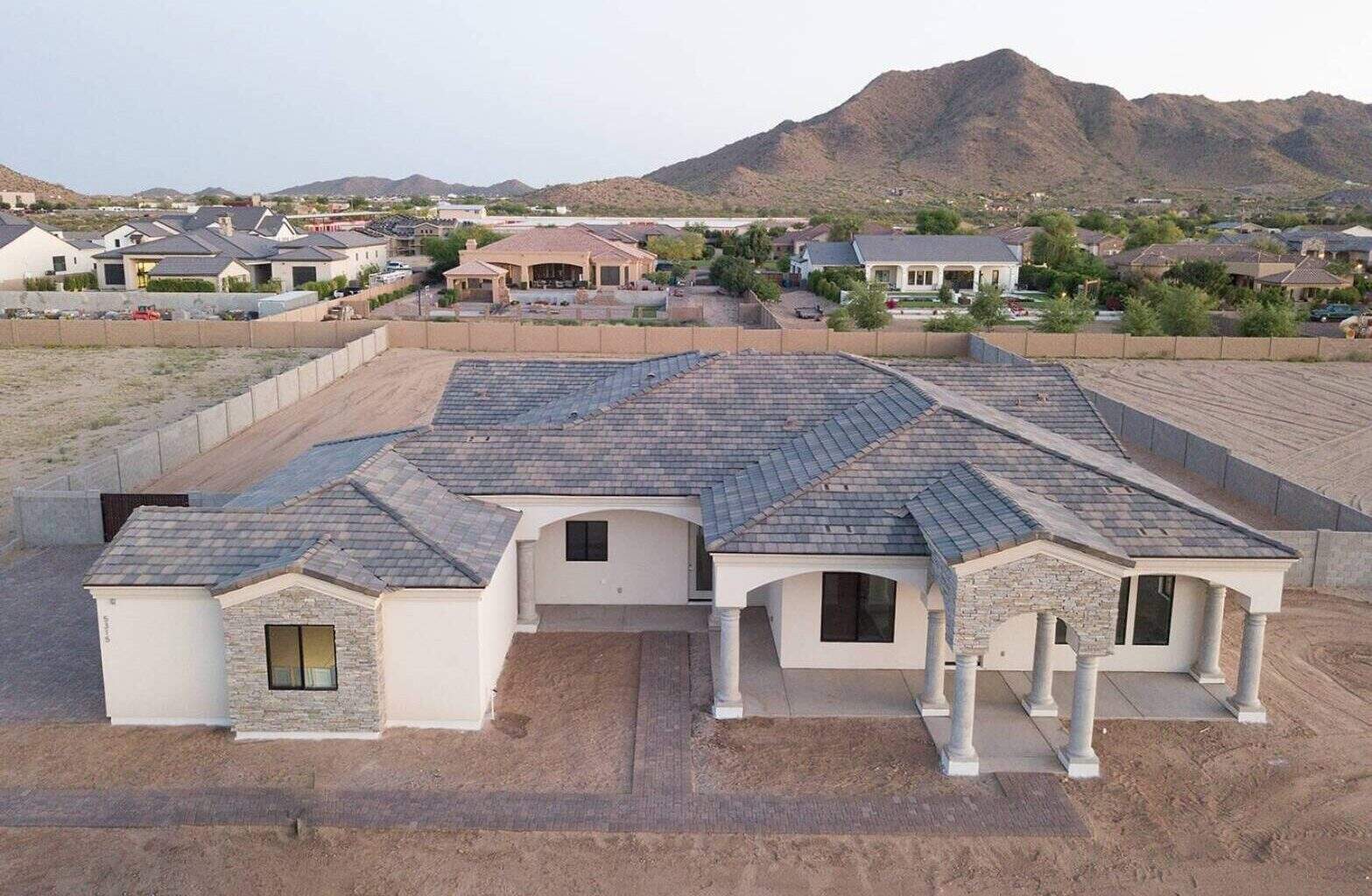 Modern custom home with a tiled roof and spacious porch in a suburban neighborhood.