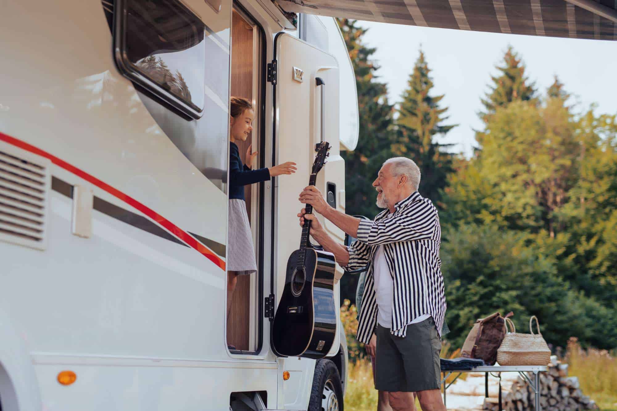 Elderly man and young girl with guitar outside RV at Nu Wavz Homes.