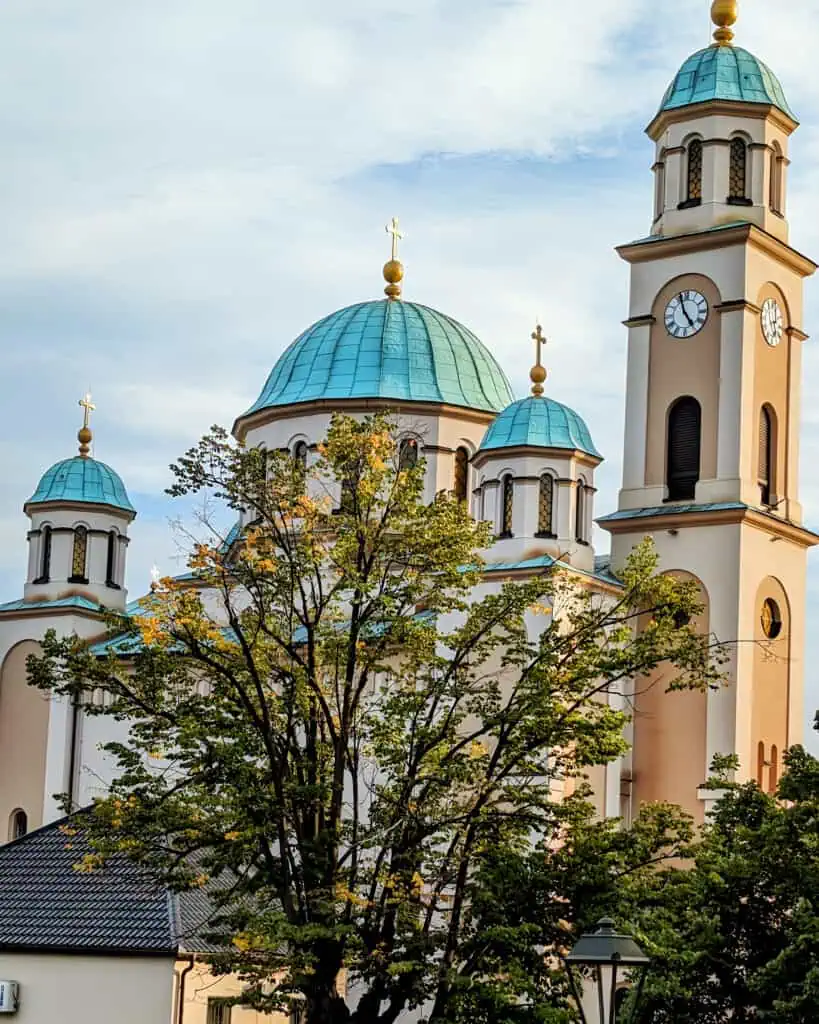 Cathedral of the Dormition of the Mother of God Tuzla Bosnia outside - cream and yellow with turquoise onion domes - Serbian orthodox