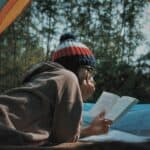 a woman reading a book in tent camping