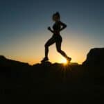 a woman running on a trail during sunrise