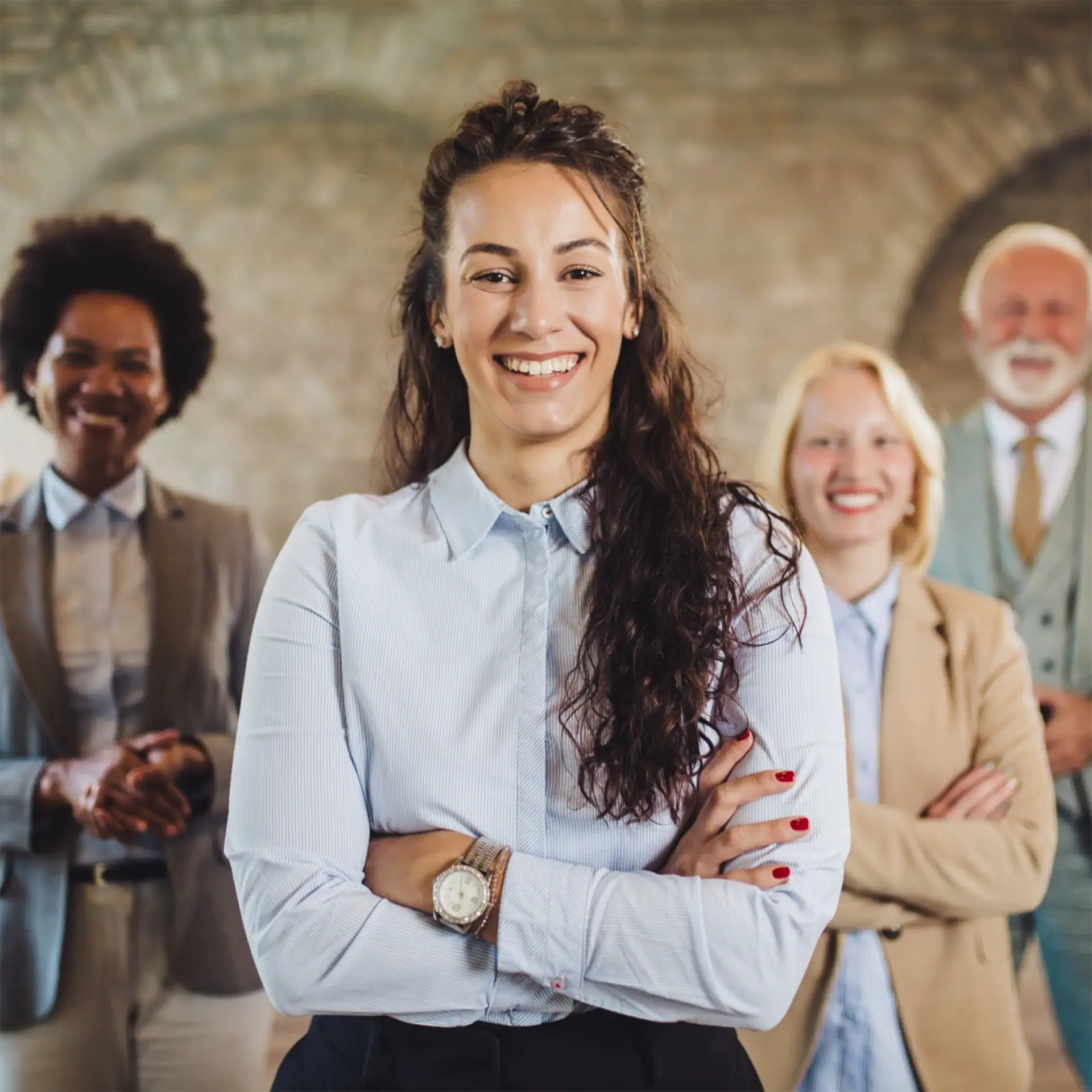 Diverse group of four professionals smiling confidently in a modern office environment.