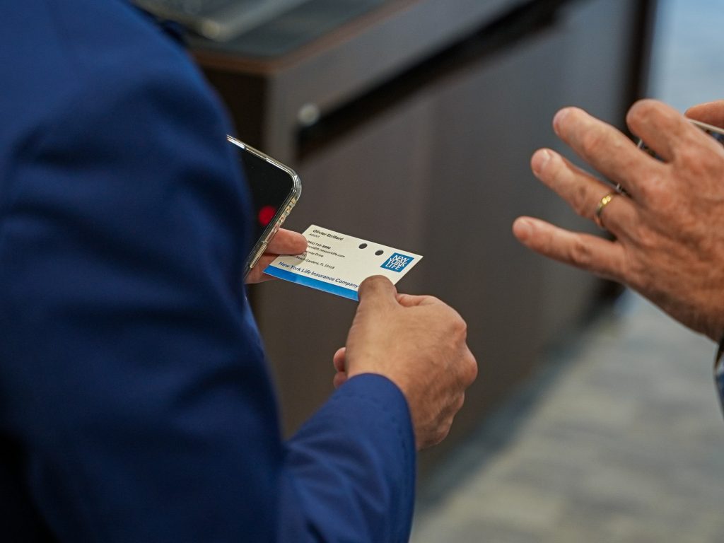 Person in blue suit exchanging business card with another individual.