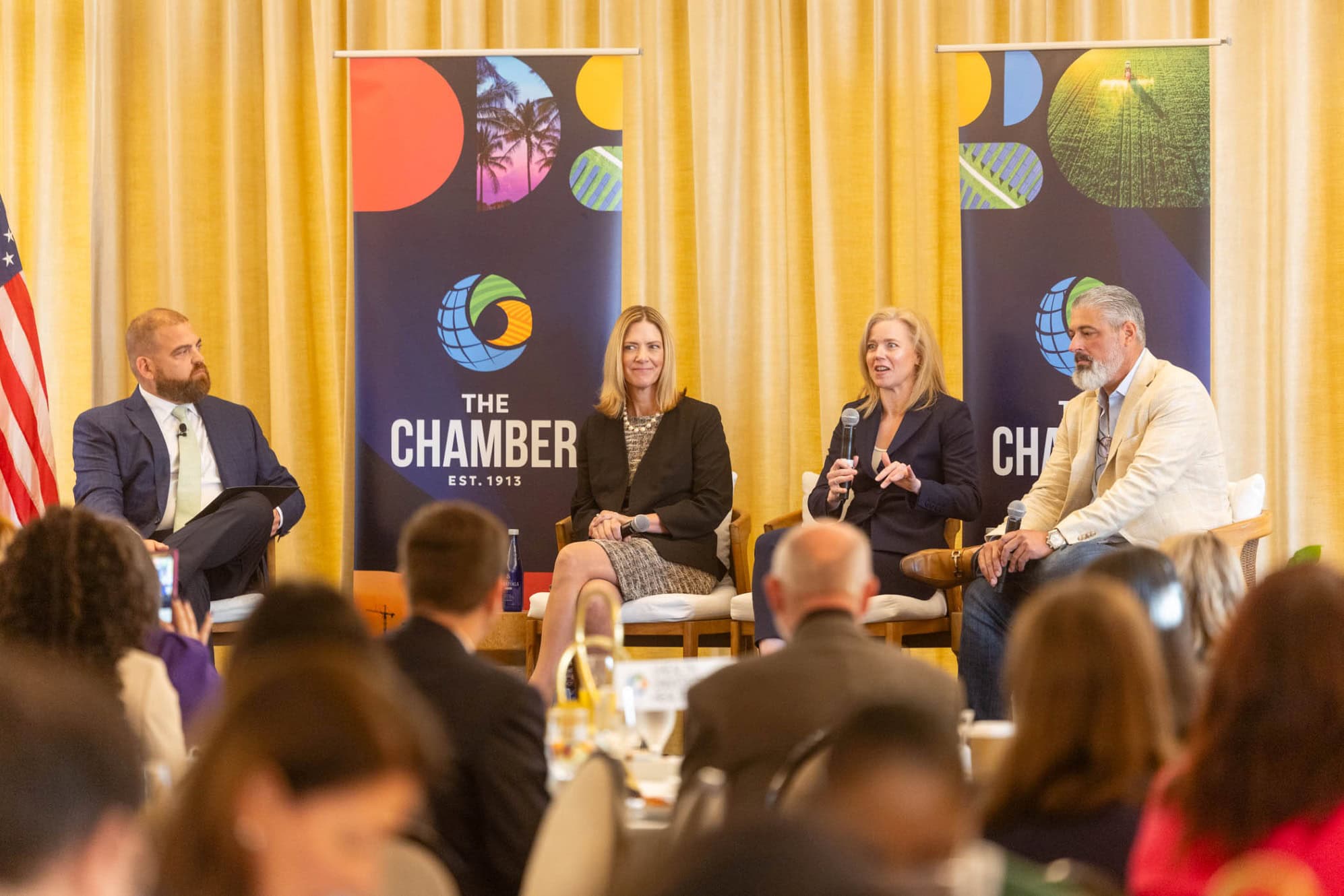 Four professionals on stage during a panel discussion at a conference.