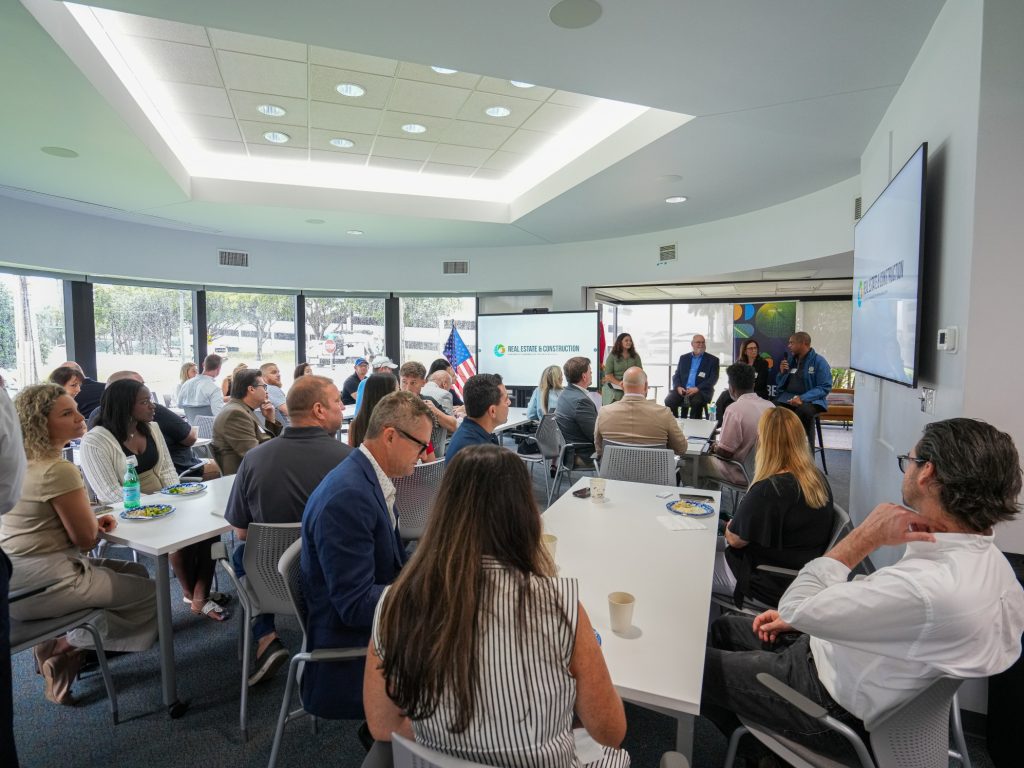 Attendees listening to speakers in a bright, modern conference room.