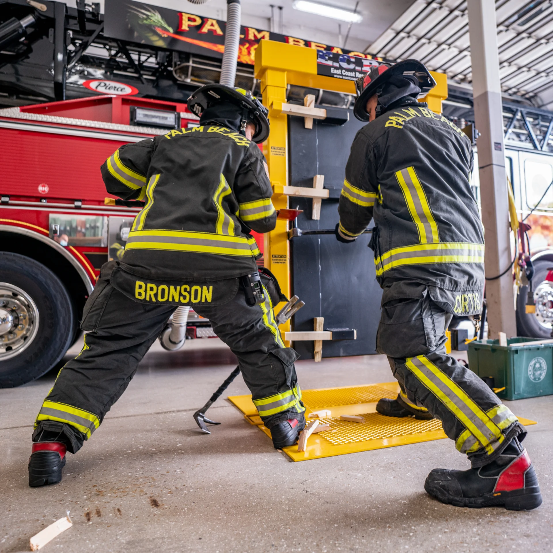 Firefighters in protective gear working on a rescue tool at a fire station.
