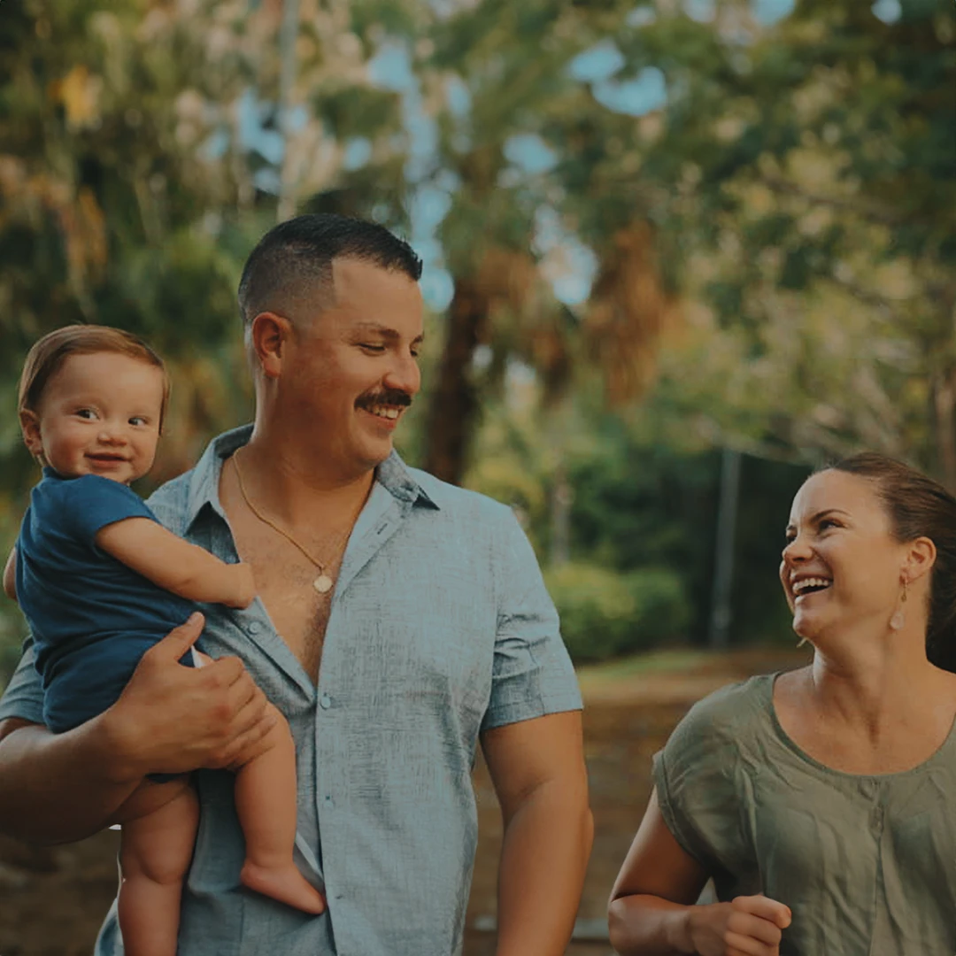 Family enjoying outdoor park with trees and sunlight in background.