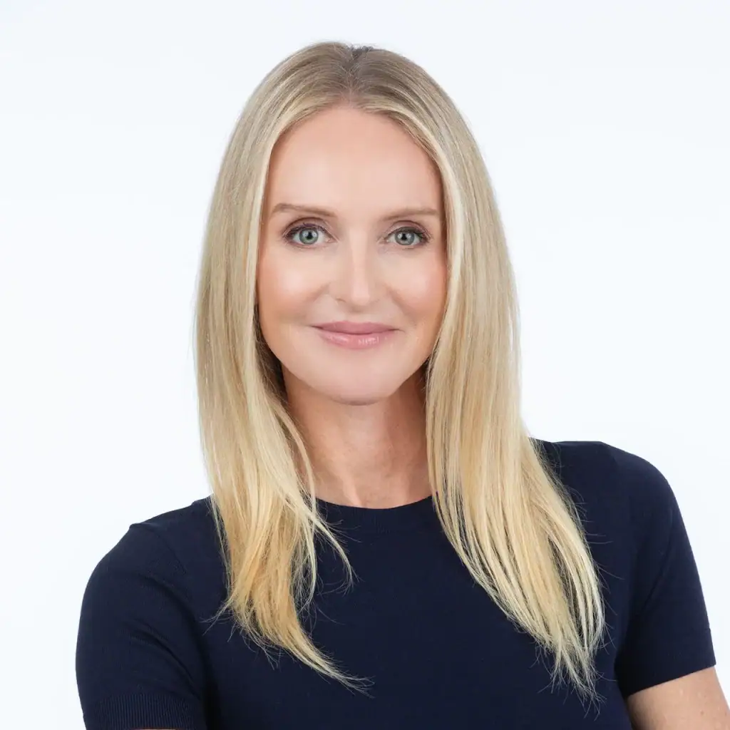 Professional woman with blonde hair in a navy blue top smiling for the camera.