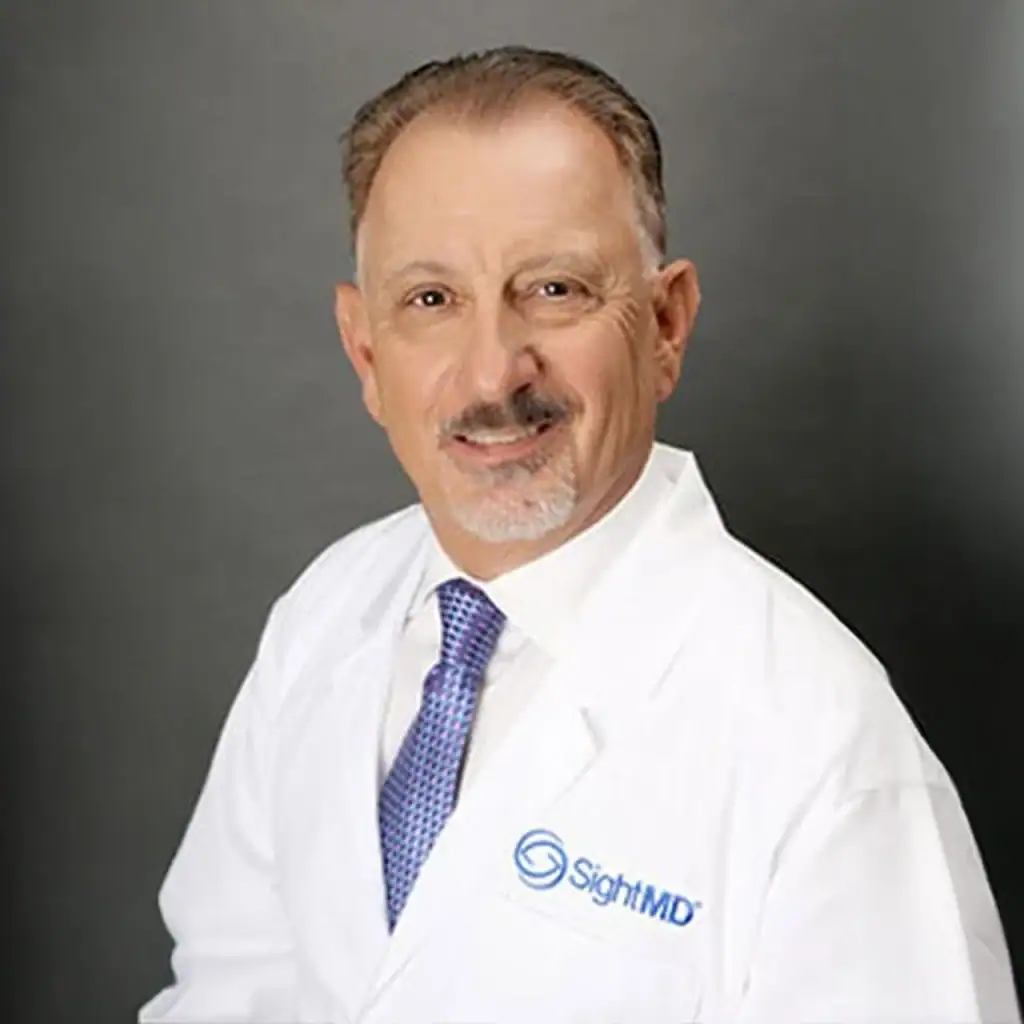 Professional portrait of a doctor in a white coat with SighMD logo.