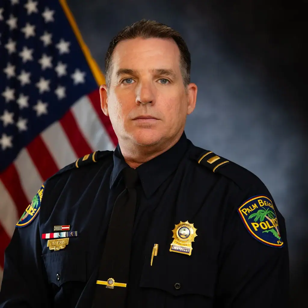 Palm Beach police officer in uniform with American flag in background.