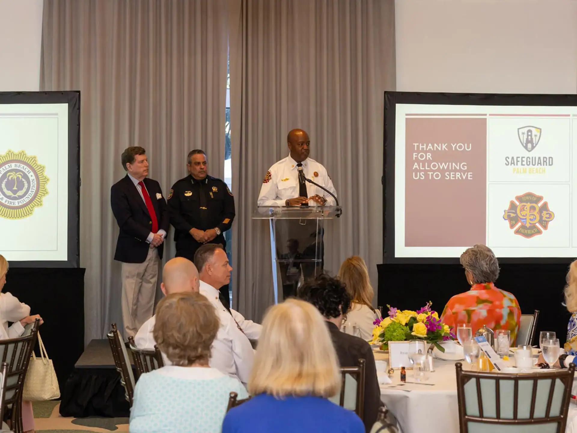 A group of people seated at a table, listening to a speaker presenting at the Palm Beach Police & Fire Foundation Safeguard Breakfast Forum