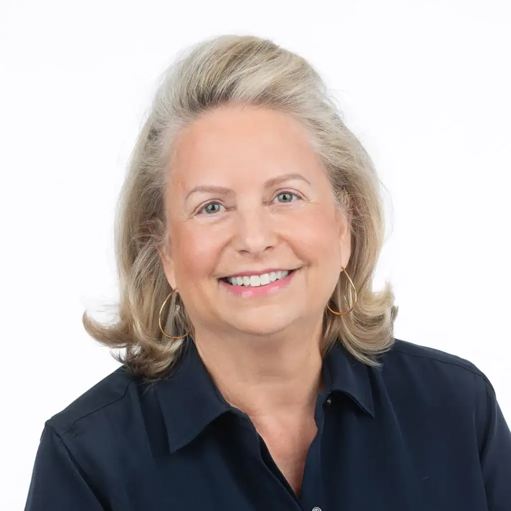 Smiling woman with blonde hair wearing a navy blue shirt, professional portrait.