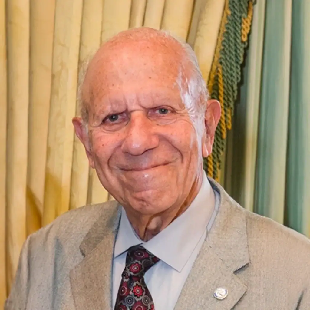 Elderly man in suit smiling at Palm Beach Police and Fire Foundation event.