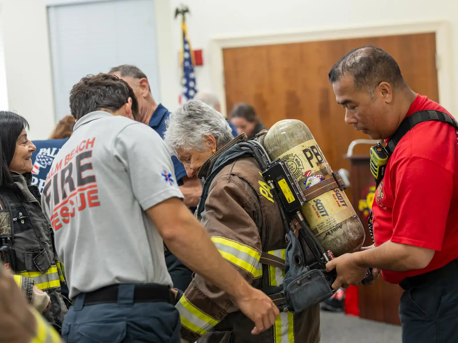 Firefighter in gear receiving assistance from emergency responders at a community event.