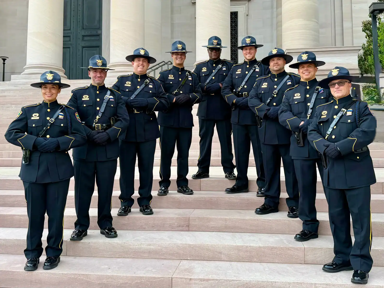 Group of police officers in uniform standing on steps in front of a government building.