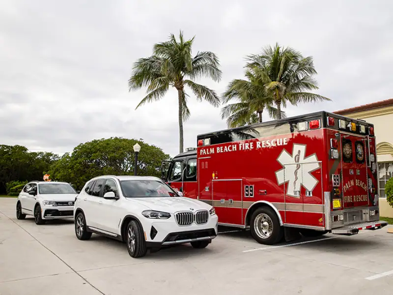Palm Beach Fire Rescue ambulance with palm trees and cars in background.