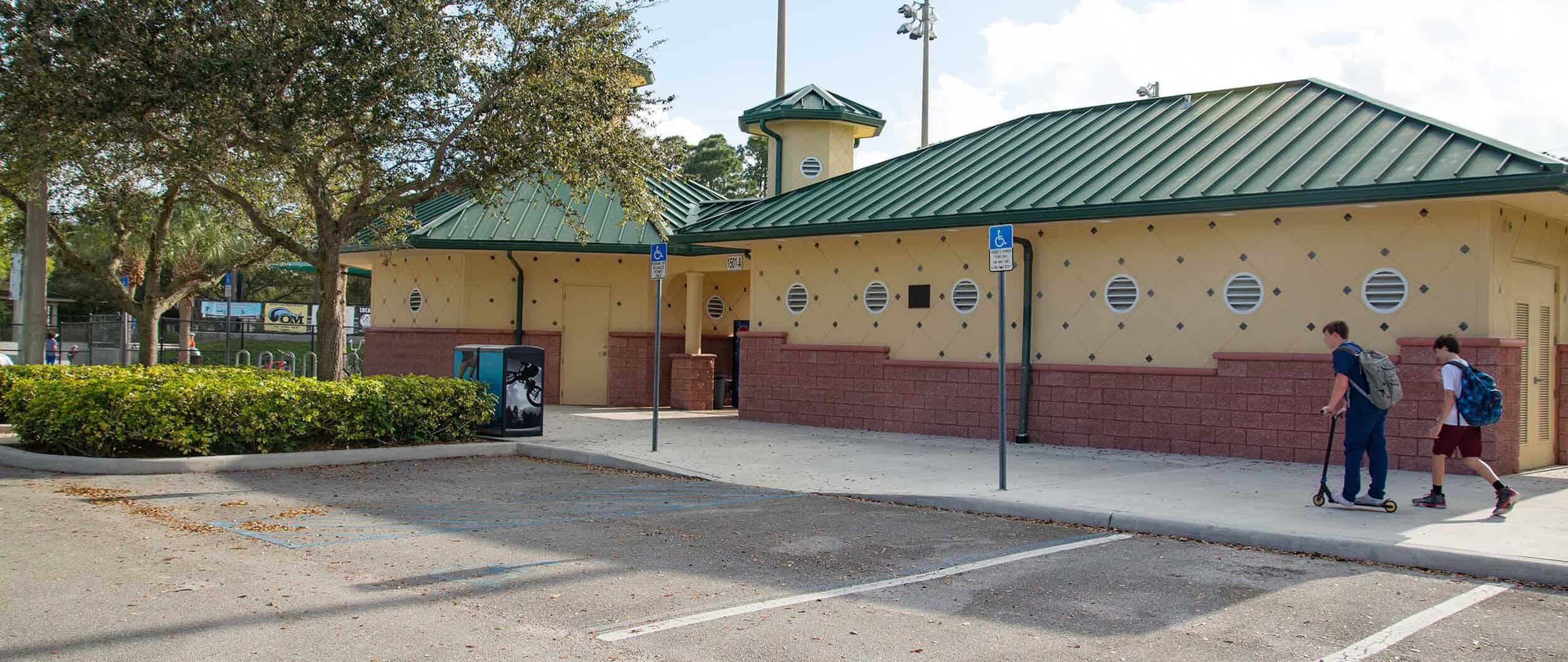 Abacoa Community Park building with parking lot and two people walking.